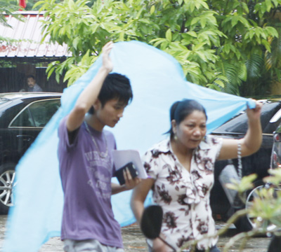 Hai mẹ con cô Trần Thị Hà che chiếc áo mưa mỏng đến trường thi.