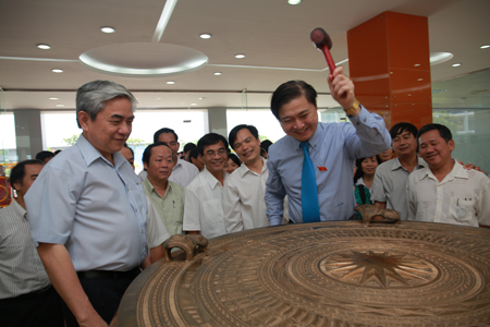 Đồng chí Phan Xuân Dũng làm lễ đánh trống đồng tại đại sảnh đại học FPT, bên cạnh là đồng chí Nguyễn Quân, bộ trưởng Bộ Khoa học và Công Nghệ.