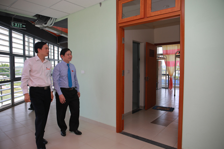 Phó Hiệu trưởng Nguyễn Việt Thắng mời đồng chí Phan Xuân Dũng thăm một gian phòng mẫu của kí túc xá Đại học FPT.