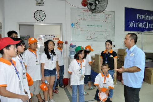 Các cháu FPT Teen được anh Nguyễn Đức Đại, nhân viên tại nhà máy, giới thiệu sơ lược về quy trình lắp máy. Ảnh: Văn Nghệ.