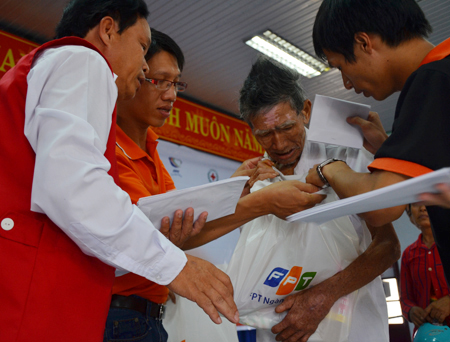 Đại diện FPT, Hội Chữ thập đỏ và Tình nguyện viên giúp một cụ ông cất quà.