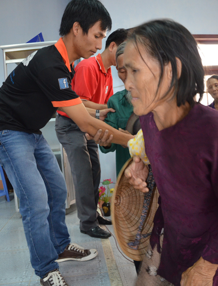 Các tình nguyện viên giúp người già và khuyết tật lên nhận quà.