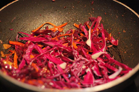 Cho tiếp bắp cải vào xào cùng, thêm vào một ít ớt bột, xào đến khi bắp cải và cà rốt chín.