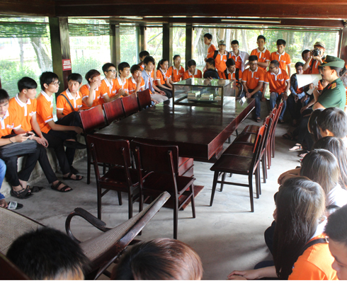 Sinh viên chăm chú lắng nghe cán bộ Bảo tàng Hồ Chí Minh, chi nhánh Quân khu 5 kể đôi nét về cuộc đời và sự nghiệp của Bác tại ngôi nhà sàn.