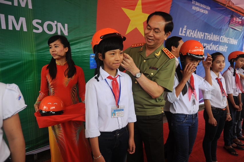 <p> Bộ trưởng Bộ Công An Trần Đại Quang cẩn thận cài quai mũ cho học sinh ngay trên quê hương mình.</p>