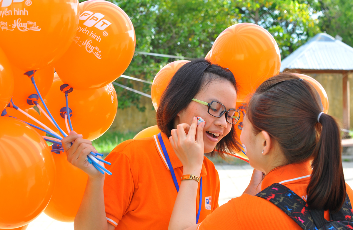 <p> Khi công tác chuẩn bị hoàn tất, một đồng nghiệp gắn miếng dán có logo FPT Telecom và dòng chữ "We love you" - Chúng tôi yêu bạn - lên má chị Trang Diệu Thư - nhân viên Kinh doanh FPT Telecom Củ Chi.</p>