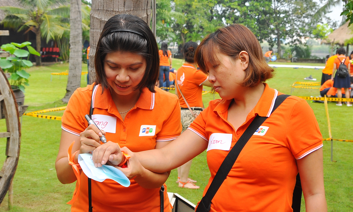 <p> Chị Nguyễn Phan Diễm Trang (trái), cán bộ nhân sự FPT Telecom Ninh Thuận, thể hiện logo của đội lên mu bàn tay đồng nghiệp Võ Thị Kim Loan, FPT Software, bằng 2 màu đen - đỏ.</p>