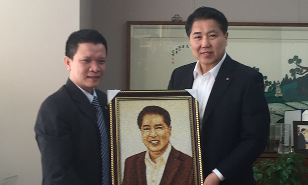 Giám đốc chi nhánh FPT Korea thay mặt tặng tranh gạo cho bác giám đốc điều hành của khách hàng]