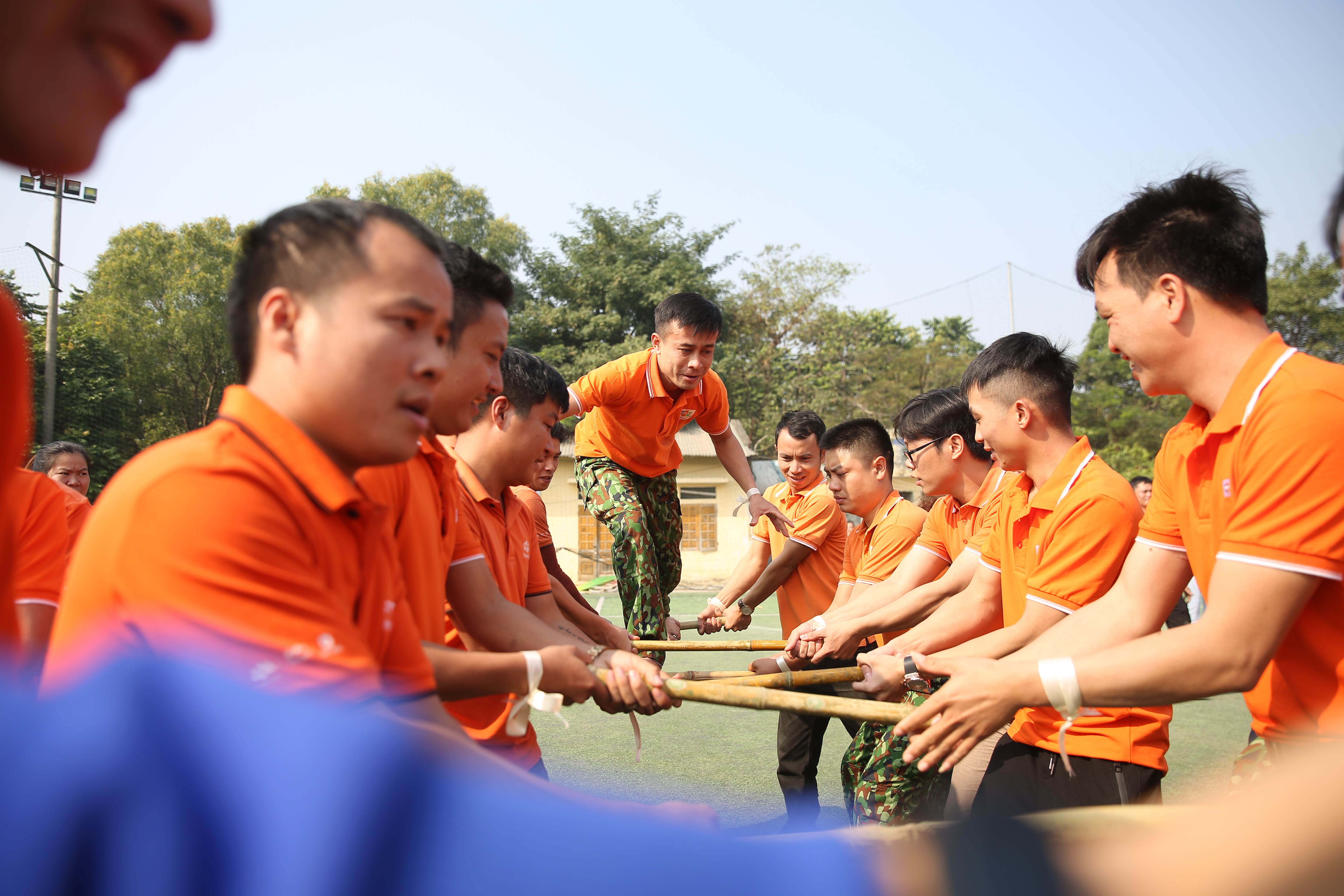  Ngay sau phần diễu hành, CBNV chi nhánh được chia thành 4 đội, tham gia phần teambuilding: màu cam, màu xanh, màu tím và màu hồng. Trò chơi đầu tiên là Vận chuyển người. Mỗi đội có 11 thành viên, chia thành 5 cặp cùng 1 thành viên được cử ra để vận chuyển qua vạch đích. Nhiệm vụ các đội là xếp 5 thanh tre tào thành đường thẳng để đưa thành viên 11 đến vạch đích nhanh nhất.